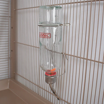 Clear feeder with 'Classic' label attached to a wire cage